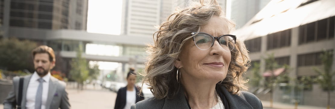 A mature businesswoman walks confidently down the street